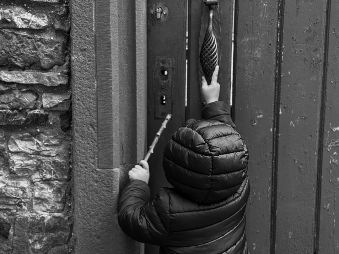 Child in puffer jacket reaching for door knocker