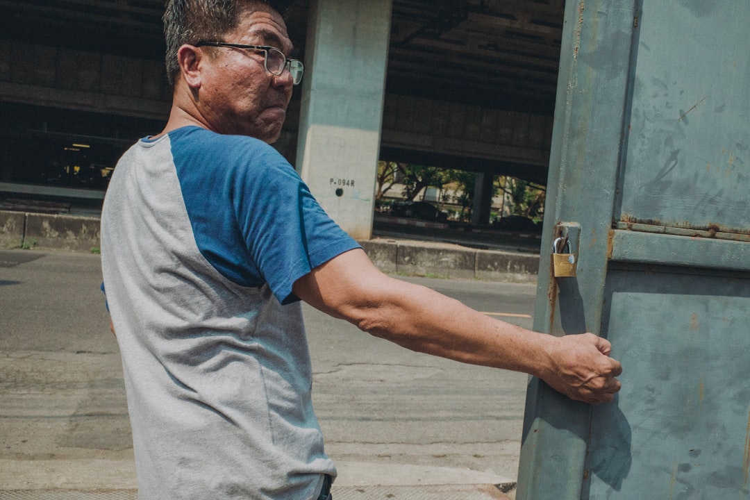 man pulling blue metal gate
